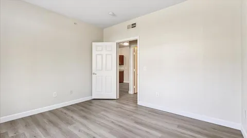 a view of an empty room with wooden floor and closet