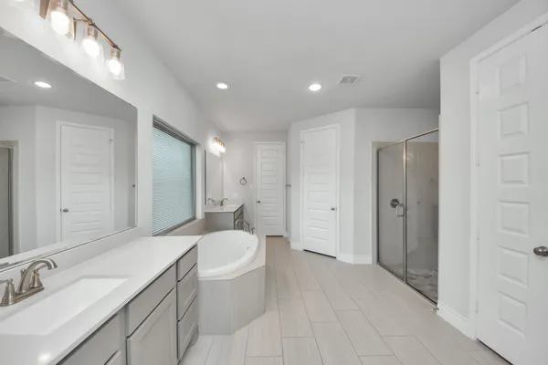 a spacious bathroom with a double vanity sink a toilet and a tub