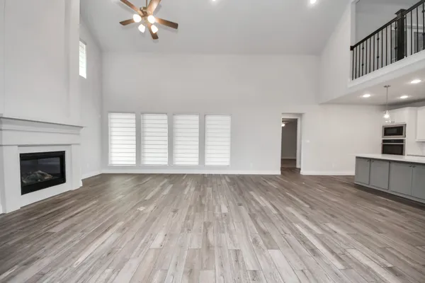 a view of an empty room with wooden floor fireplace and a window
