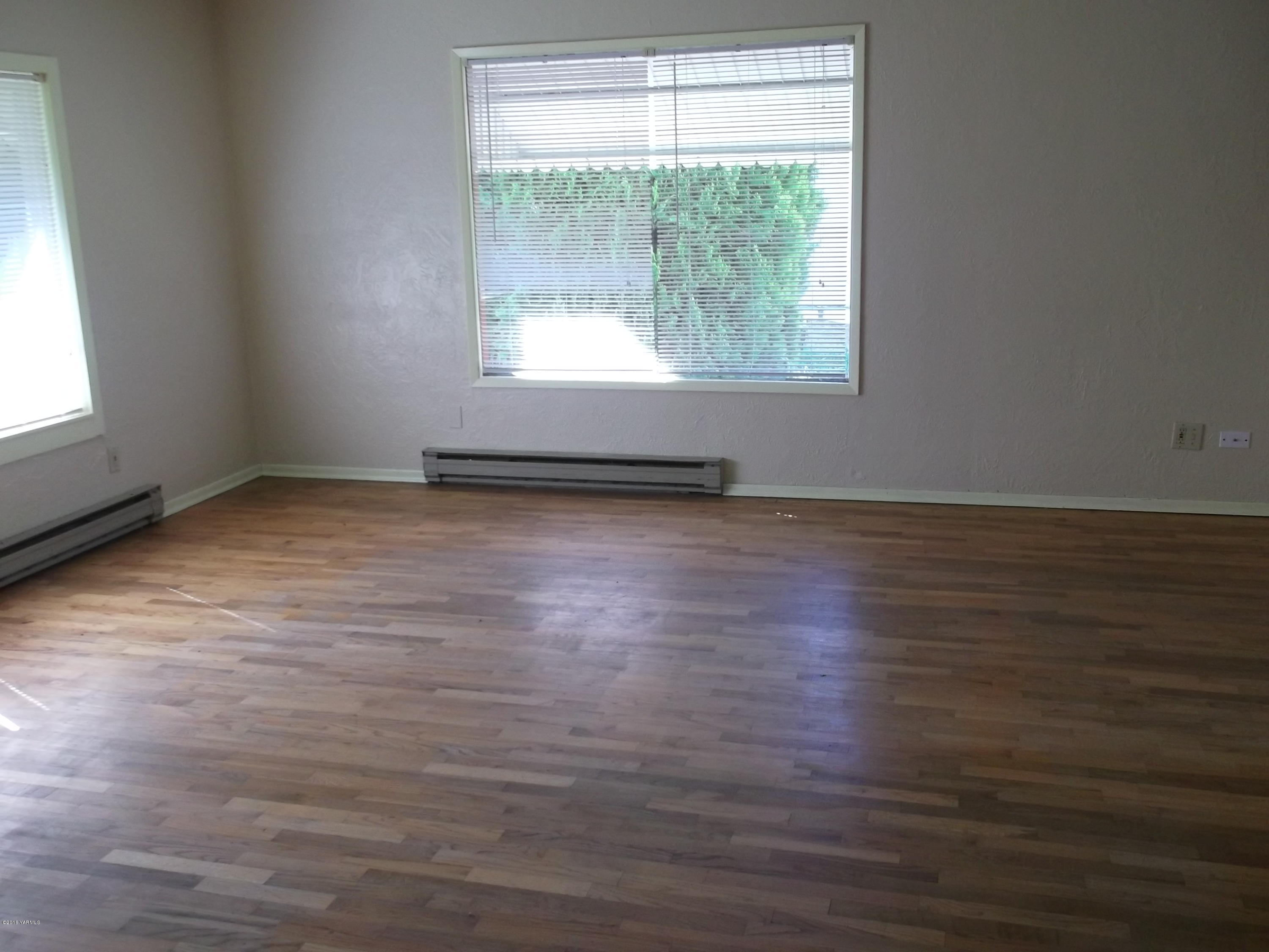 419 Cemetery Road Sunnyside, WA 98944 - Photo 2 of 15 an empty room with wooden floor and windows