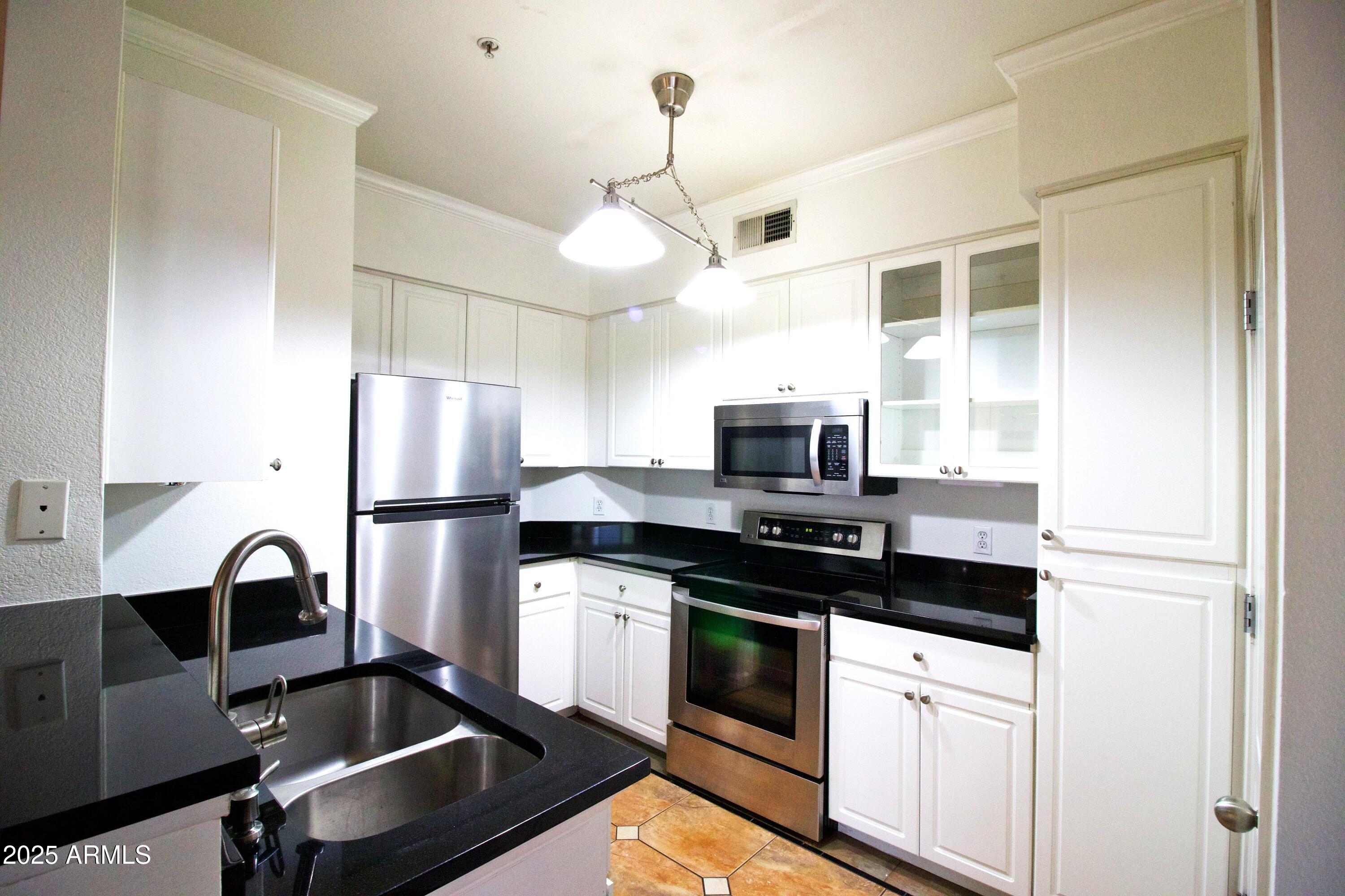 1701 East Colter Street, Unit 370 Phoenix, AZ 85016 - Photo 4 of 20 a kitchen with stainless steel appliances a refrigerator sink and white cabinets