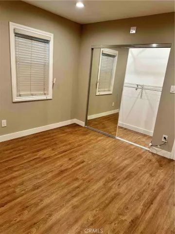 an empty room with wooden floor and mirror