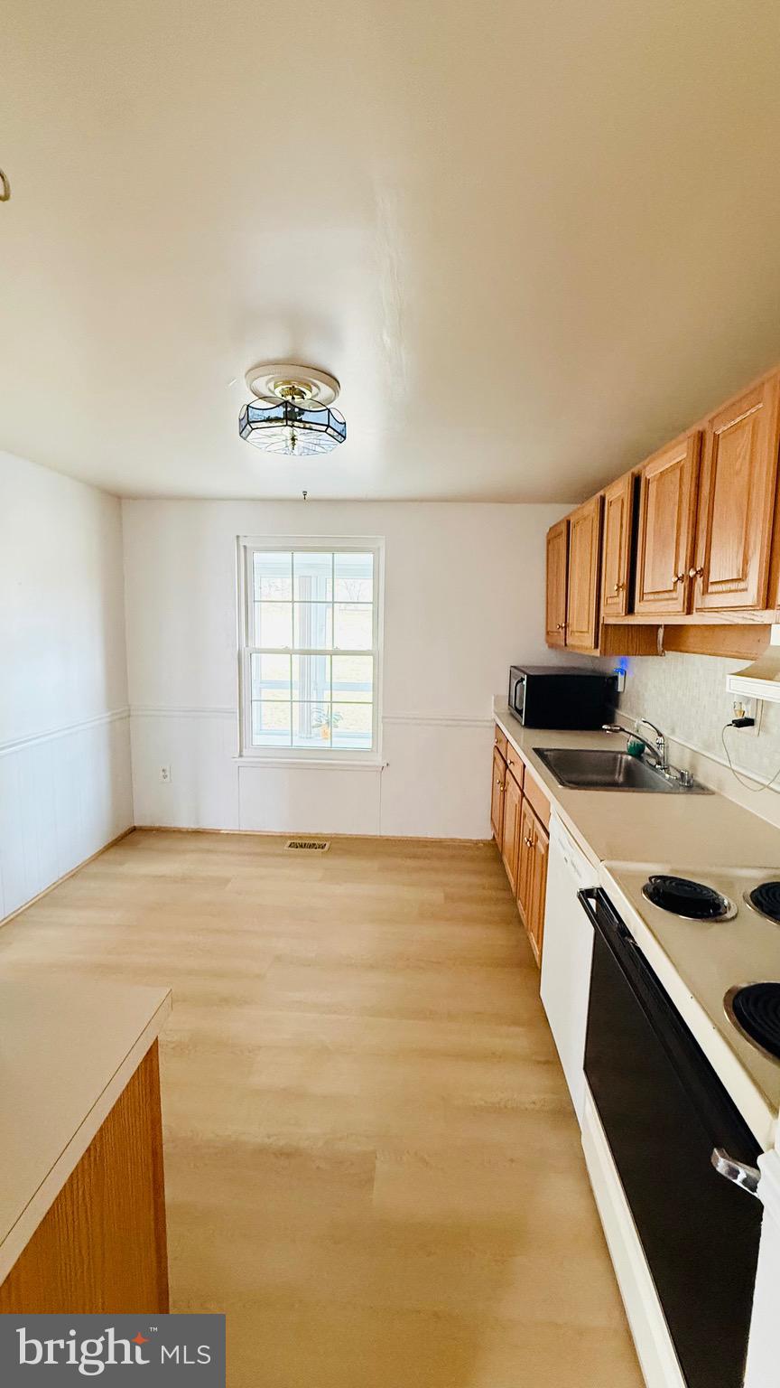 6915 Bugledrum Way Columbia, MD 21045 - Photo 7 of 25 a view of a kitchen with kitchen island a sink wooden floor and a large window
