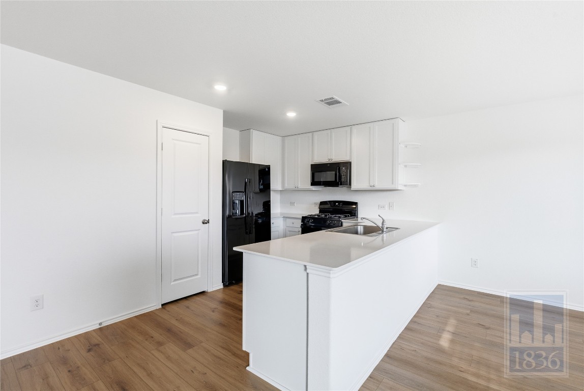2213 Cyclone Drive Lockhart, TX 78644 - Photo 6 of 26 a kitchen with stainless steel appliances a refrigerator oven a sink with white cabinets and wooden floor