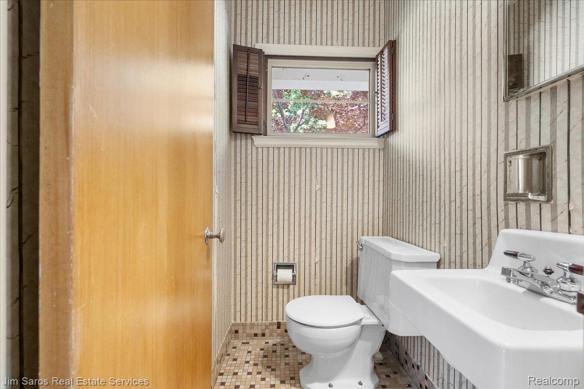 1010 Nottingham Road Grosse Pointe, MI 48230 - Photo 12 of 30 Compact bathroom featuring vertical striped wallpaper, a wall-mounted sink, and a commode
