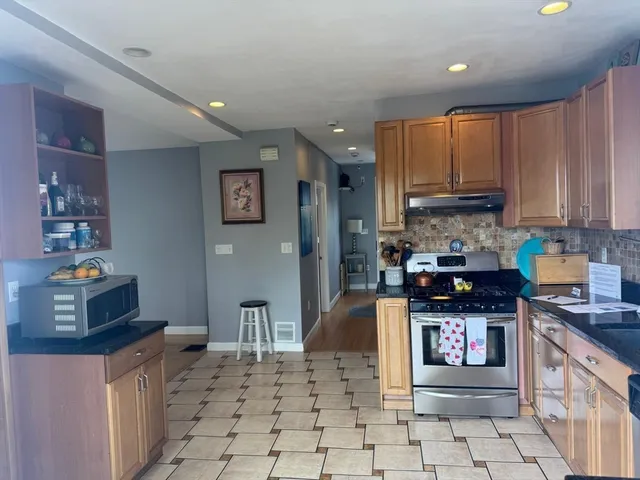 a kitchen with stainless steel appliances granite countertop a stove top oven a sink a counter space and cabinets