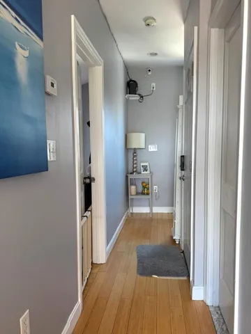 a view of a hallway with wooden floor and a bathroom