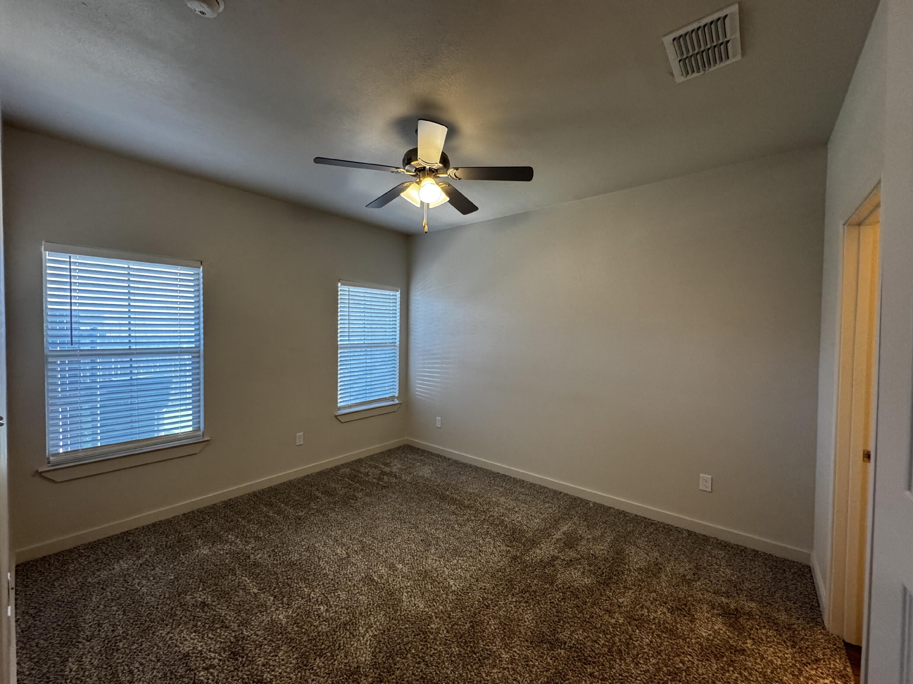 2613 135th Street Lubbock, TX 79423 - Photo 11 of 15 en empty room with windows and chandelier fan