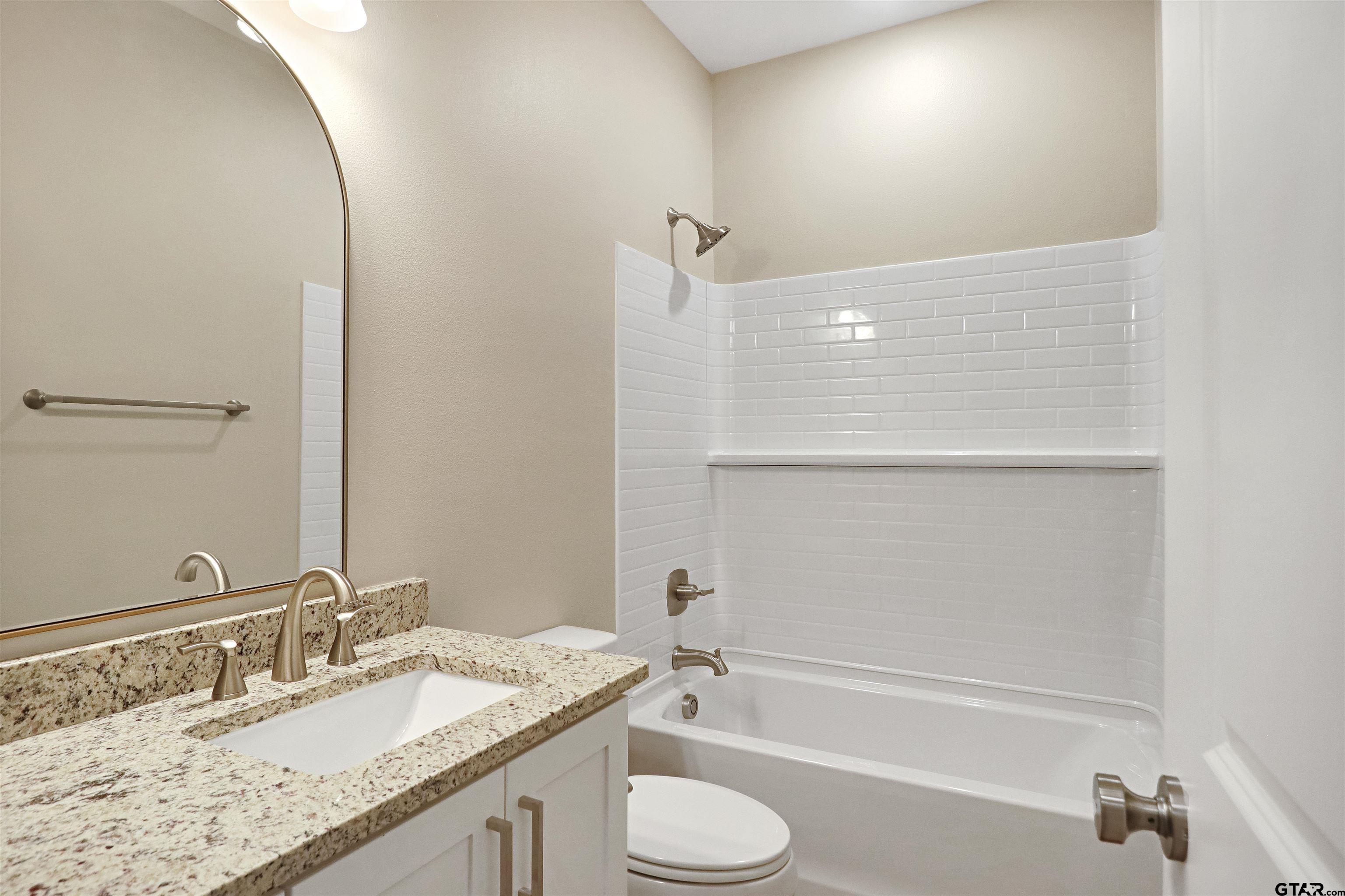3053 Guinn Farms Road Tyler, TX 75707 - Photo 23 of 32 a bathroom with a granite countertop sink toilet and shower