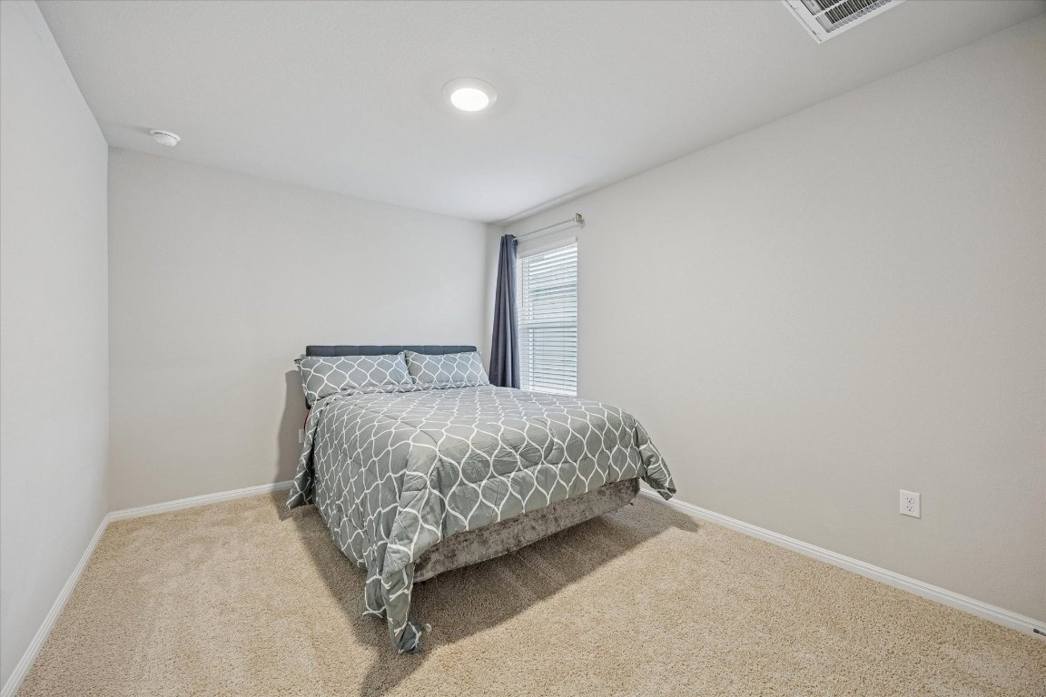 724 Aster Place Bastrop, TX 78602 - Photo 11 of 16 a bed sitting in a room next to a lamp