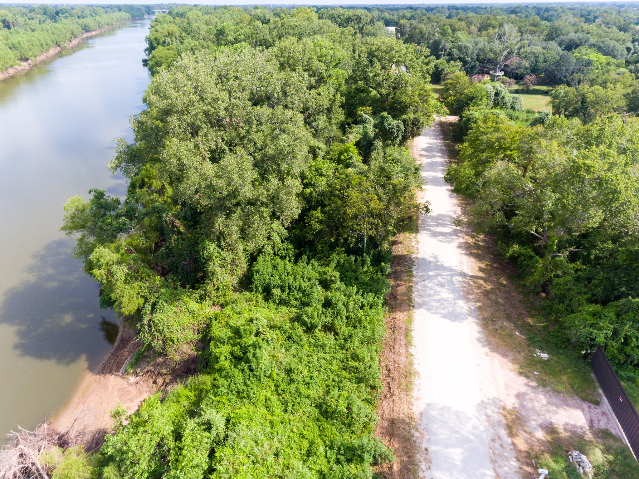 1353 Seidel Road Brookshire, TX 77423 - Photo 29 of 35 This aerial photo showcases a tranquil riverside location with a lush, tree-lined dirt road leading to a secluded area. Ideal for nature lovers seeking privacy and scenic views.