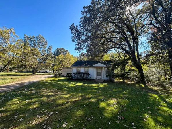 a view of a house with a big yard and large trees