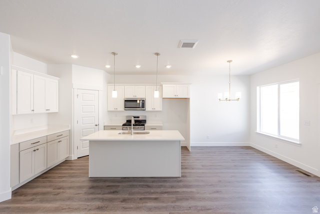 5287 South Acacia Drive, Unit 714 Mapleton, UT 84664 - Photo 4 of 21 Open-concept kitchen and dining area featuring wood-finish flooring, white cabinetry, a kitchen island with sink, stainless steel appliances, and a chandelier
