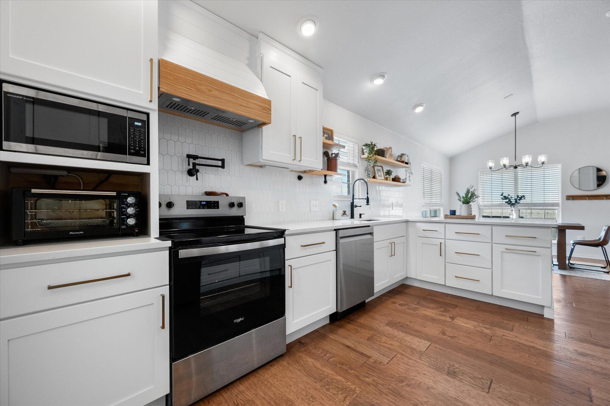 1429 Fm 211 Wilson, TX 79381 - Photo 13 of 43 a kitchen with white cabinets stainless steel appliances and wooden floor