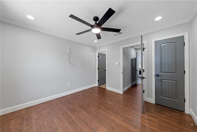 a view of an empty room with wooden floor and a ceiling fan