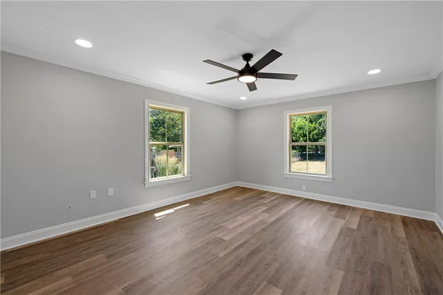 a view of empty room with wooden floor and fan