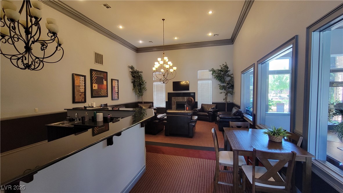 6650 West Warm Springs Road, Unit 1032 Las Vegas, NV 89118 - Photo 5 of 17 Dining space with a tile fireplace, a chandelier, crown molding, a wainscoted wall, and recessed lighting