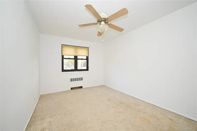 an empty room with a window and ceiling fan
