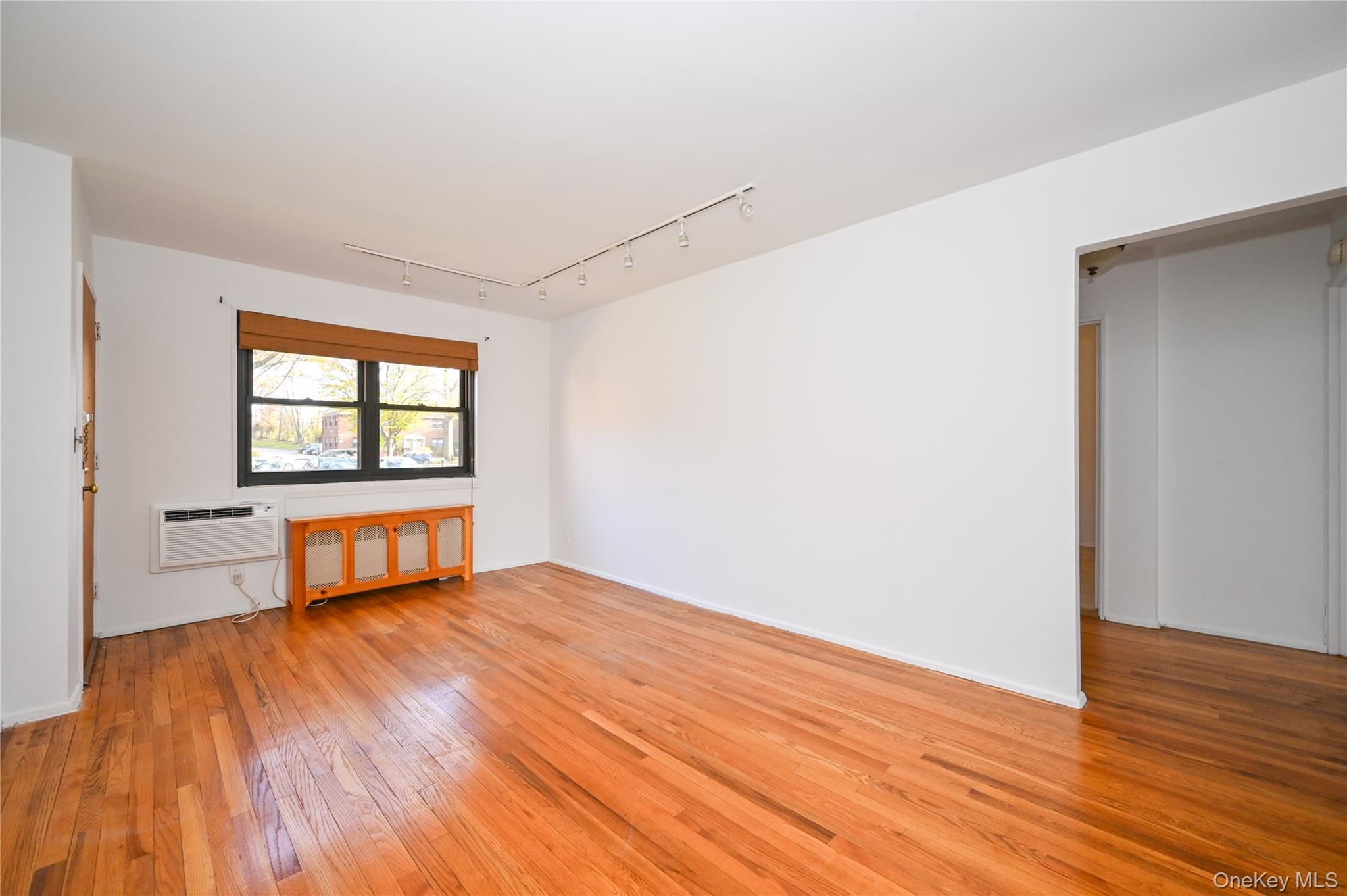 245-12 62nd Avenue, Unit G/3 LOWER Queens, NY 11362 - Photo 5 of 18 an empty room with wooden floor and windows
