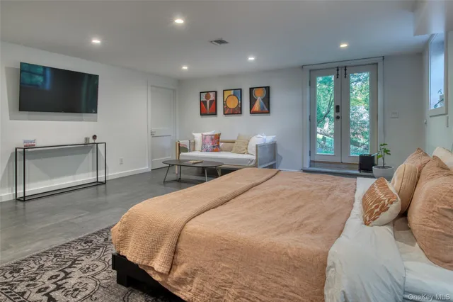 a spacious bedroom with a bed and a flat screen tv