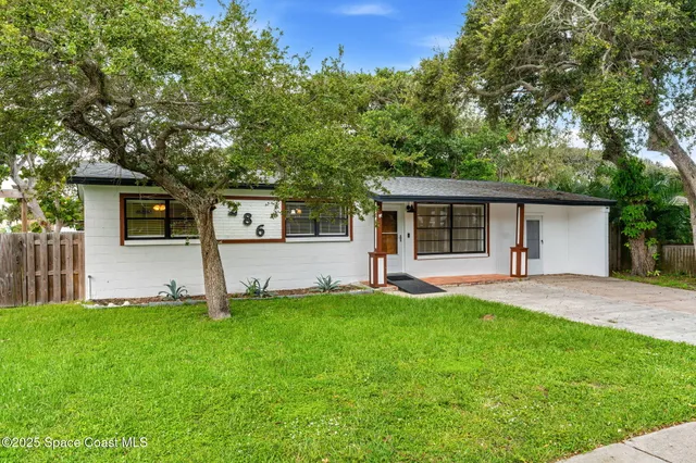 front view of a house with a yard and a large tree