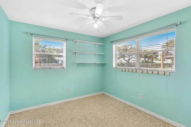 an empty room with a window and a fan