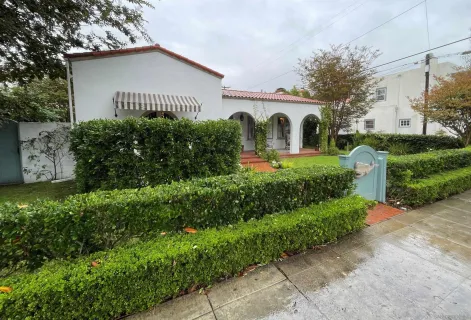 a front view of house with garden and trees
