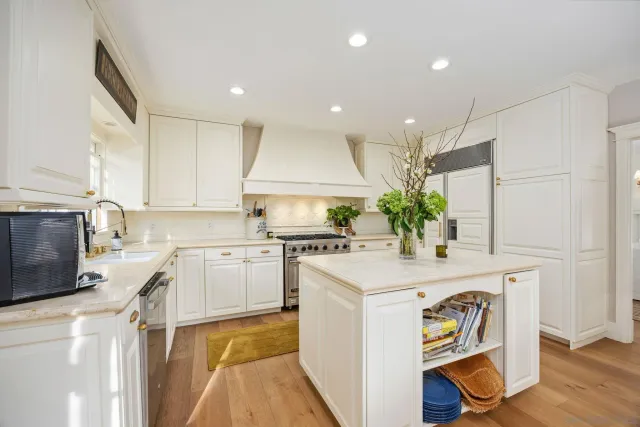 a kitchen with a sink dishwasher stove and white cabinets with wooden floor