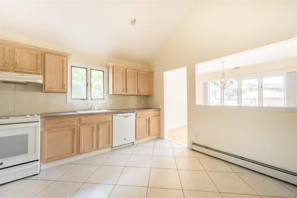 a kitchen with granite countertop white cabinets white appliances a sink and a window