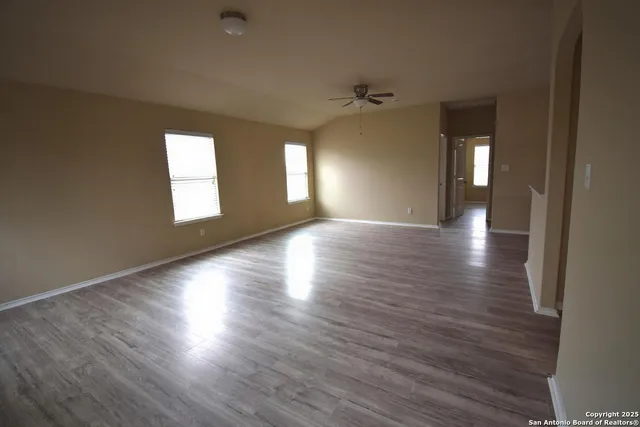 an empty room with wooden floor and windows