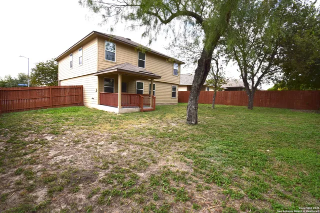 a view of a house with a yard and large trees