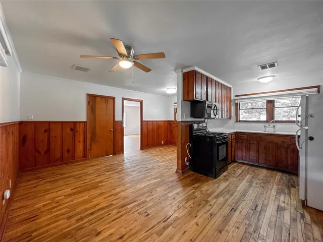a living room with stainless steel appliances kitchen island granite countertop wooden floors and a large window