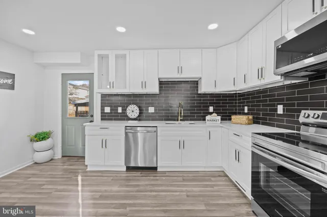 a kitchen with stainless steel appliances a stove a sink cabinets and a wooden floor