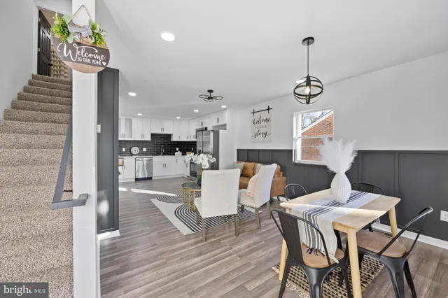 a living room with couches chairs and kitchen view with wooden floor