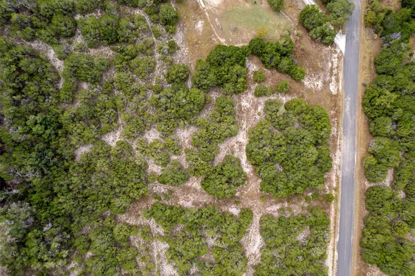 an aerial view of residential house with outdoor space and trees all around