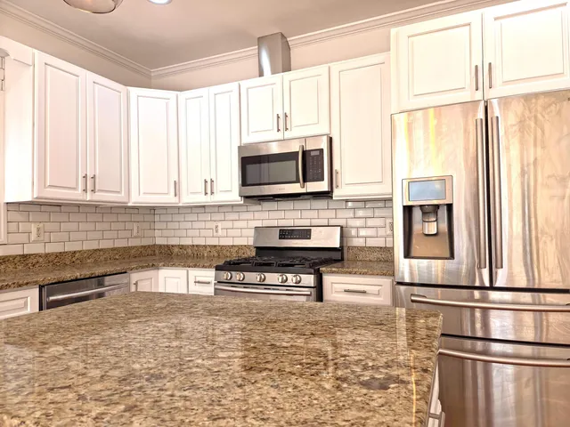 a kitchen with stainless steel appliances granite countertop a refrigerator a stove a sink and a microwave