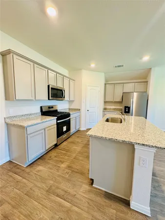 a kitchen with granite countertop a sink a counter top space stainless steel appliances and cabinets