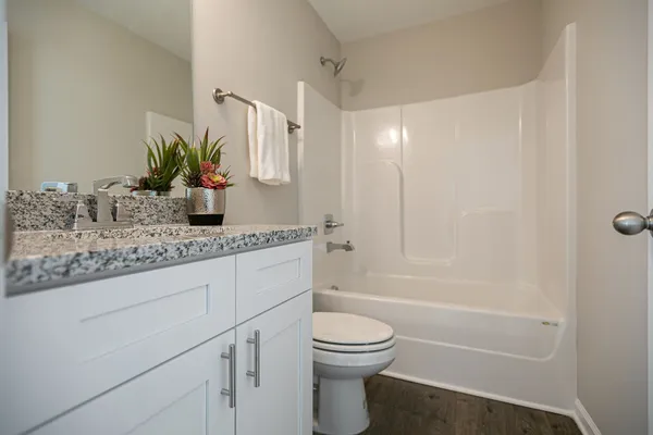 a bathroom with a granite countertop toilet sink and mirror
