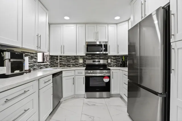 a kitchen with stainless steel appliances a stove a sink a microwave a refrigerator and cabinets