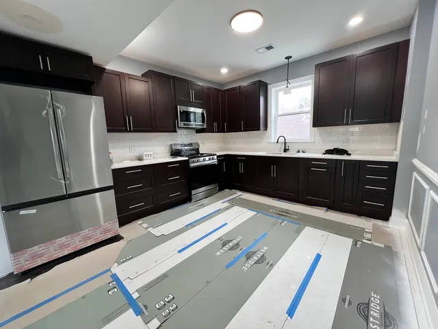 a large kitchen with stainless steel appliances granite countertop a refrigerator and a sink