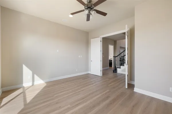 a view of a room with wooden floor and a ceiling fan
