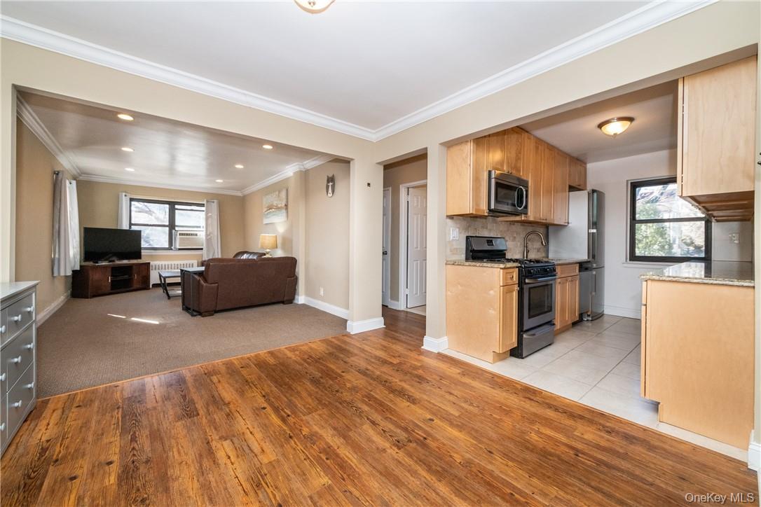 50 White Oak Street, Unit 3G New Rochelle, NY 10801 - Photo 8 of 16 a large room with kitchen island a stove a refrigerator a sink a dining table and chairs with wooden floor