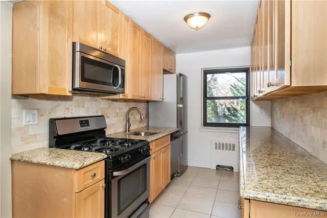 a kitchen with stainless steel appliances granite countertop a stove a sink and a microwave