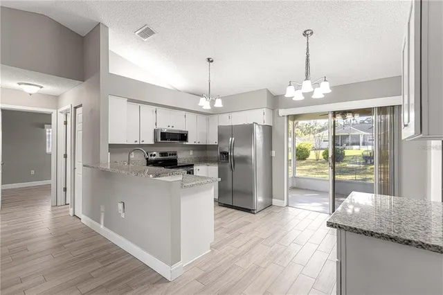 a kitchen with stainless steel appliances granite countertop a refrigerator a oven a stove and a wooden floors