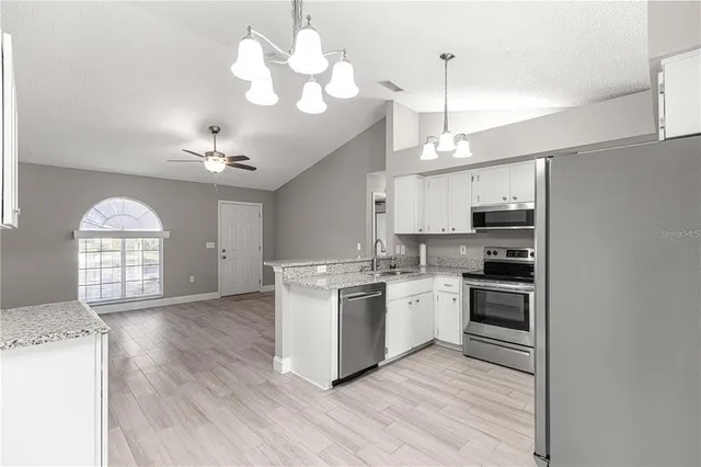 a kitchen with a stove a sink dishwasher a refrigerator and a fireplace with wooden floor