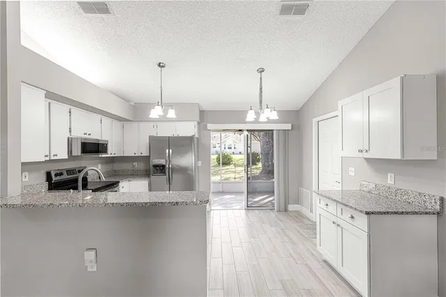 a large kitchen with granite countertop a large counter top appliances and cabinets