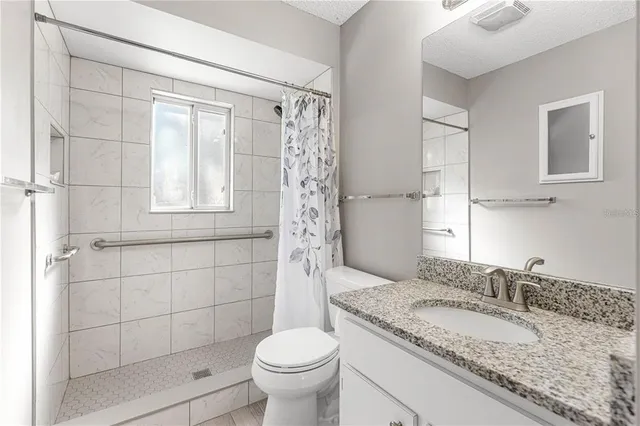 a bathroom with a granite countertop sink toilet and shower