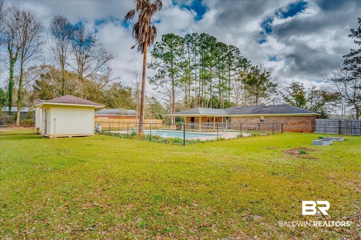 440 Dykes Road Mobile, AL 36608 - Photo 38 of 49 View of yard with a storage unit, an outbuilding, a fenced in pool, and fence