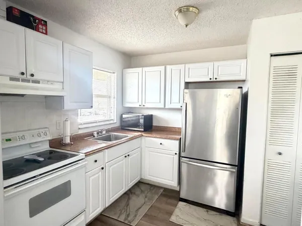 a white refrigerator freezer sitting in a kitchen with stainless steel appliances granite countertop a refrigerator sink and cabinets