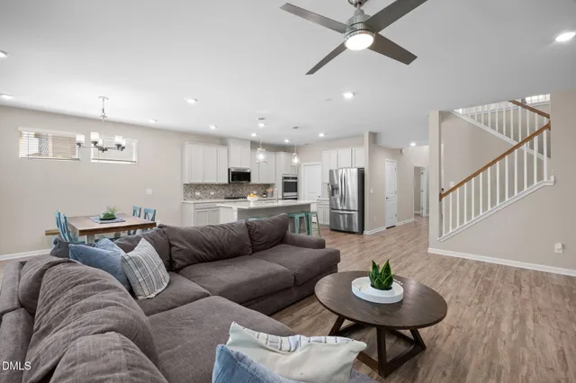 a living room with furniture kitchen view and a wooden floor